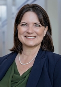 female in navy suit with pearl necklace
